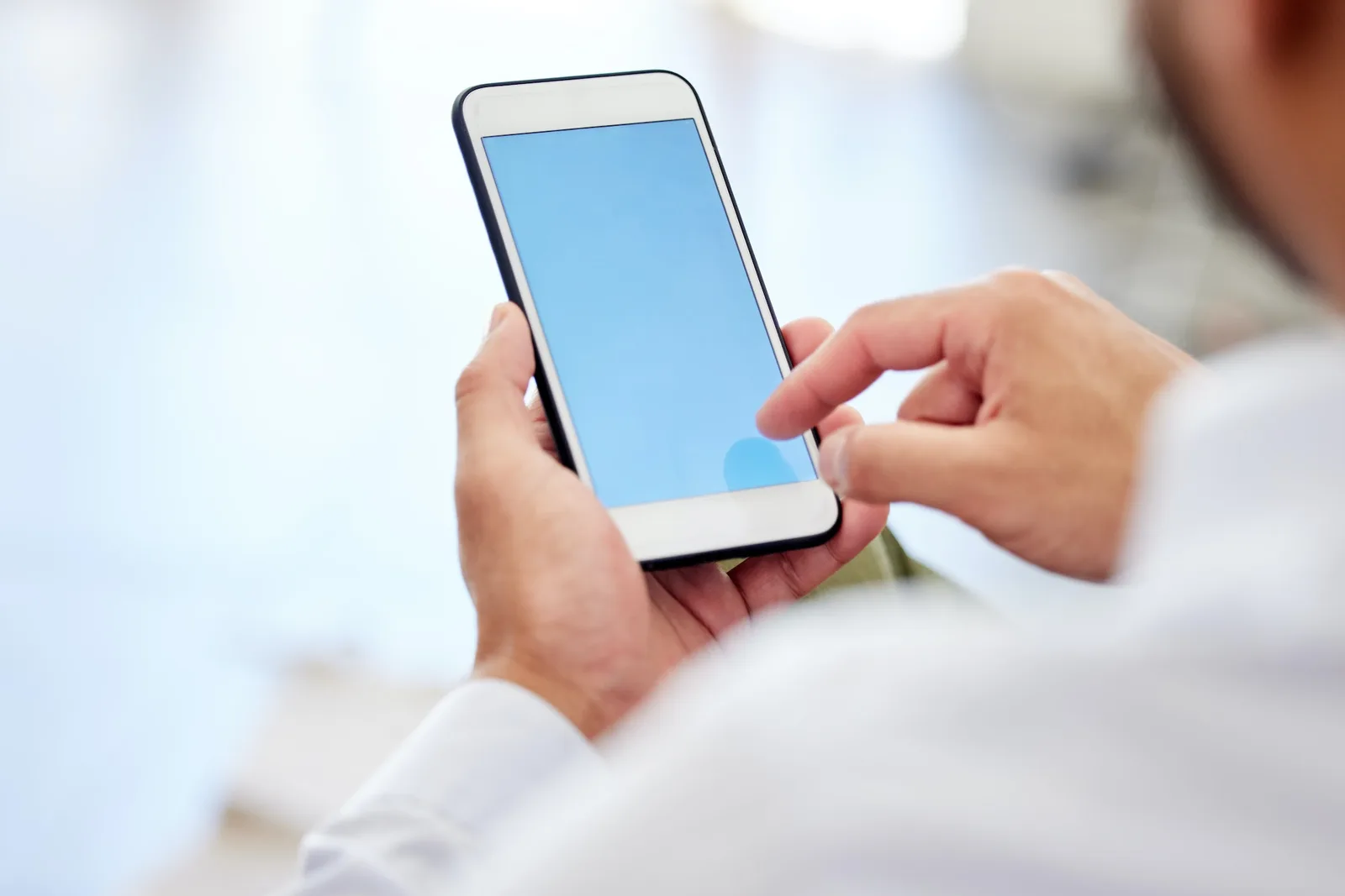 Blank blue screen of a phone with a businessman typing or scrolling the internet. Closeup of corpor